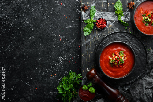 Food. Tomato Gaspacho Soup on a black stone plate. Top view. Free space for your text.