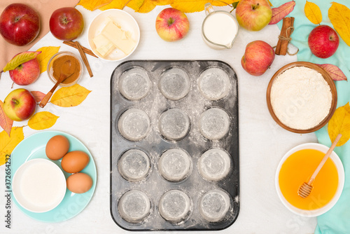 ingredients and recipe for homemade Apple cupcakes and muffins, top view light background, yellow leaves. the concept of fall baking and fall harvest. the cupcake mold is floured