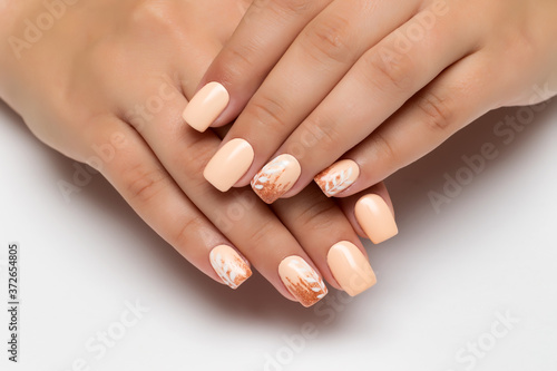 Peach wedding manicure with gold sequins and white branches, leaves on square long nails close-up on a white background.