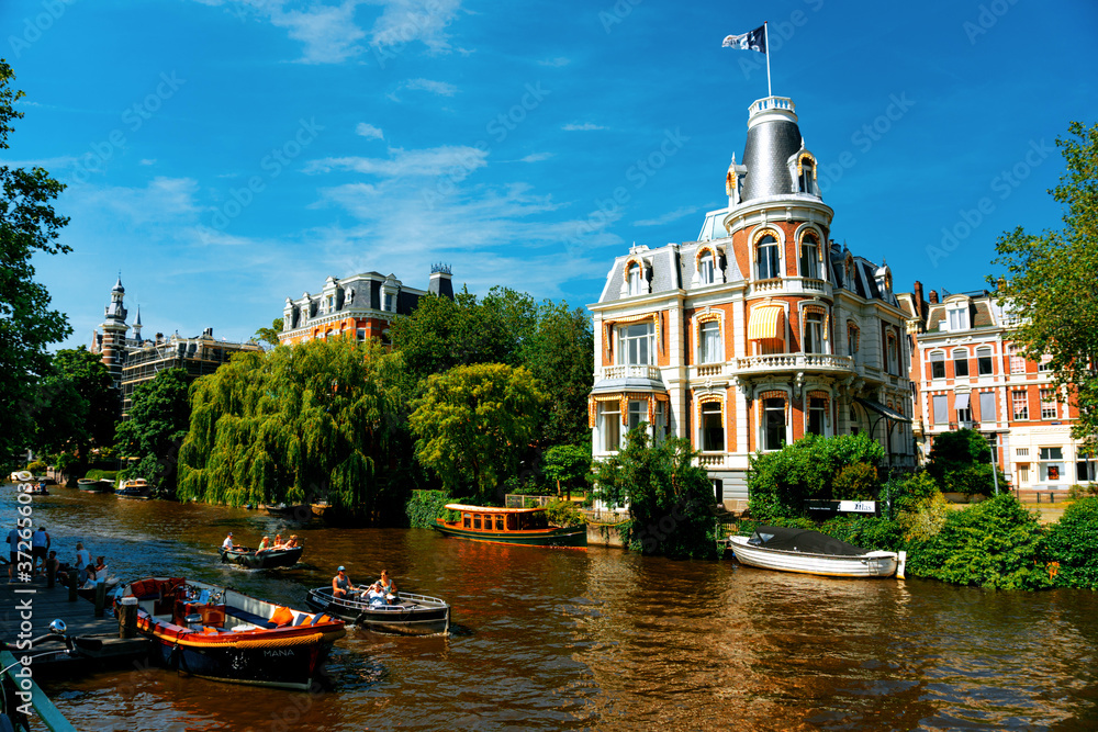 Canal in Amsterdam with boats and beautiful historic house