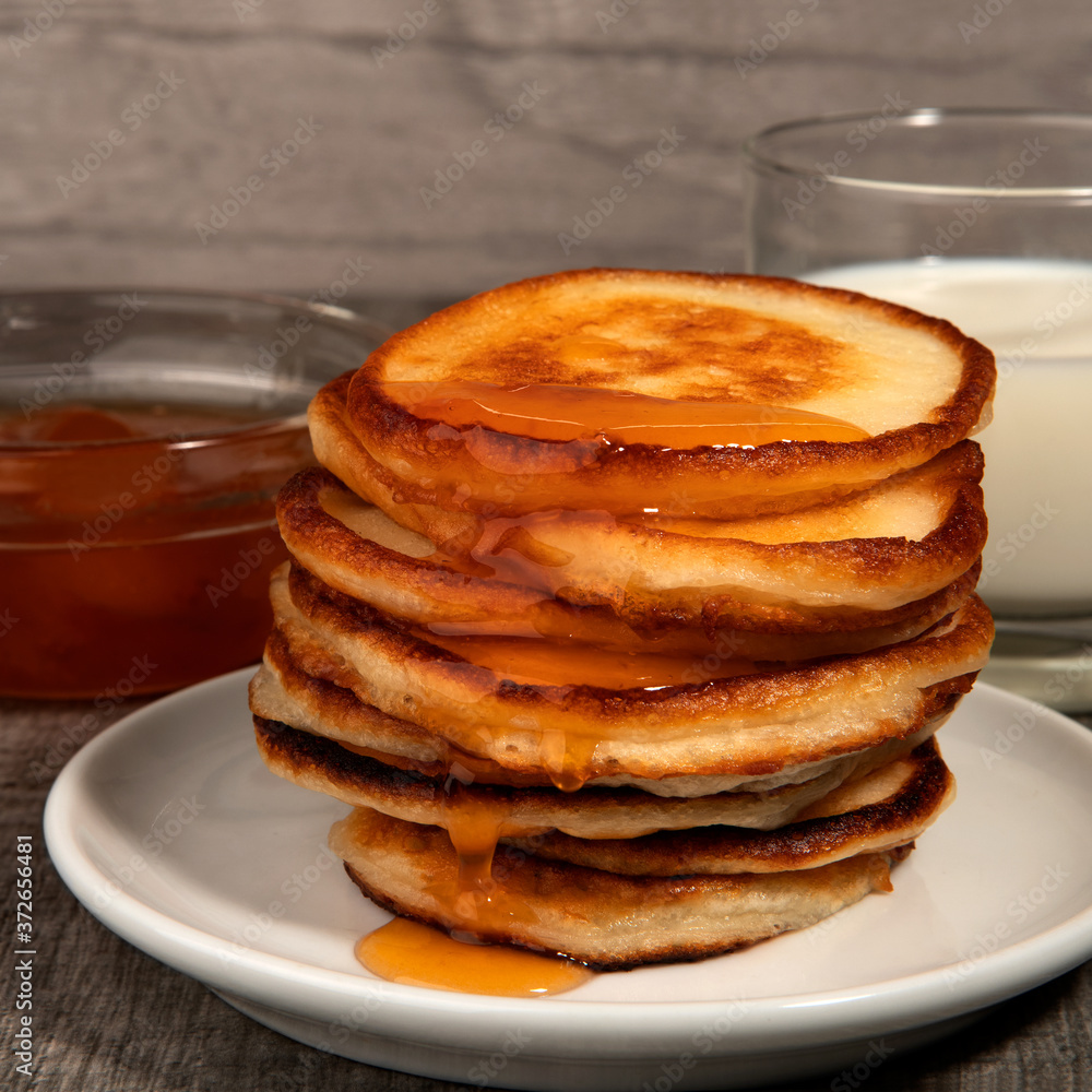 Several pancakes, glass of milk and apricot jam on wood background. Several pancakes, glass of milk and apricot jam on wood background.