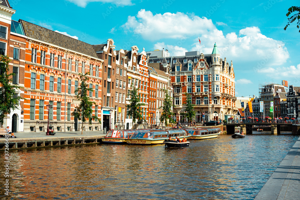 Canal in Amsterdam with pleasure boat and historic buildings