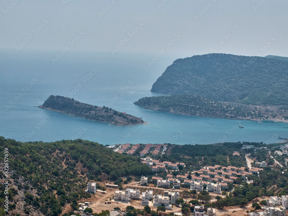 Village on the pine-covered mountain range slope and island at the Mediterranean sea