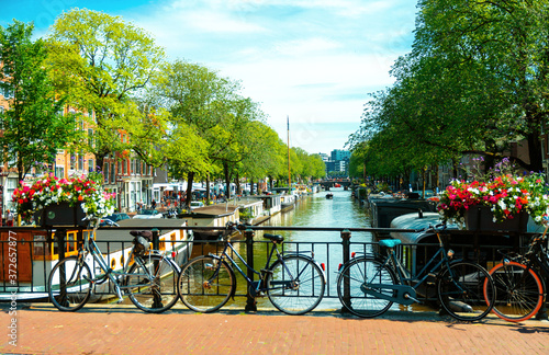 Beautiful summer sunrise, heritage canals of Amsterdam, The Netherlands, with vibrant flowers and bicycles on a bridge. June 2019 photo