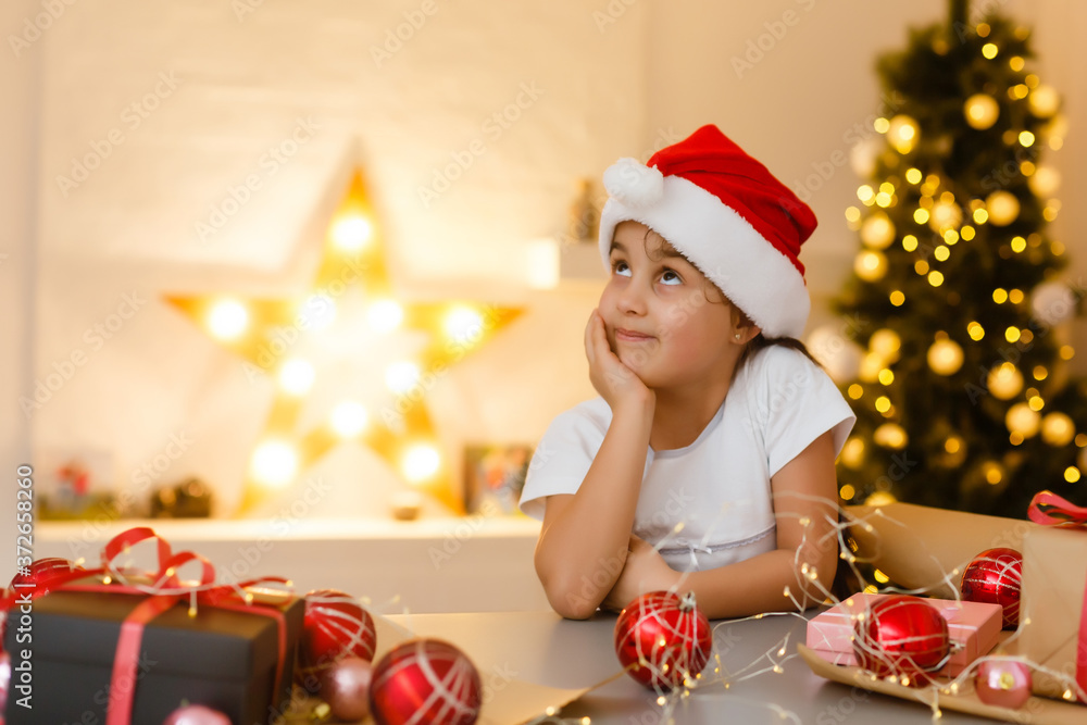 child girl in red hat preparing gifts for christmas at home, cozy holiday interior