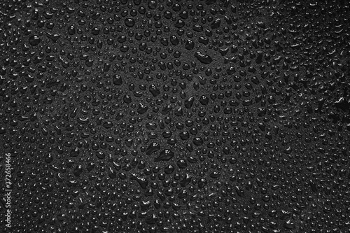 Water droplets on black background. Close-up photo of small water drops on black background.