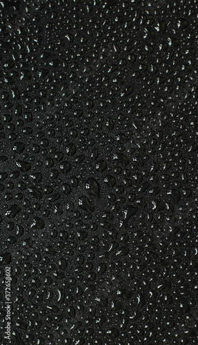 Water droplets on black background. Close-up photo of small water drops on black background.