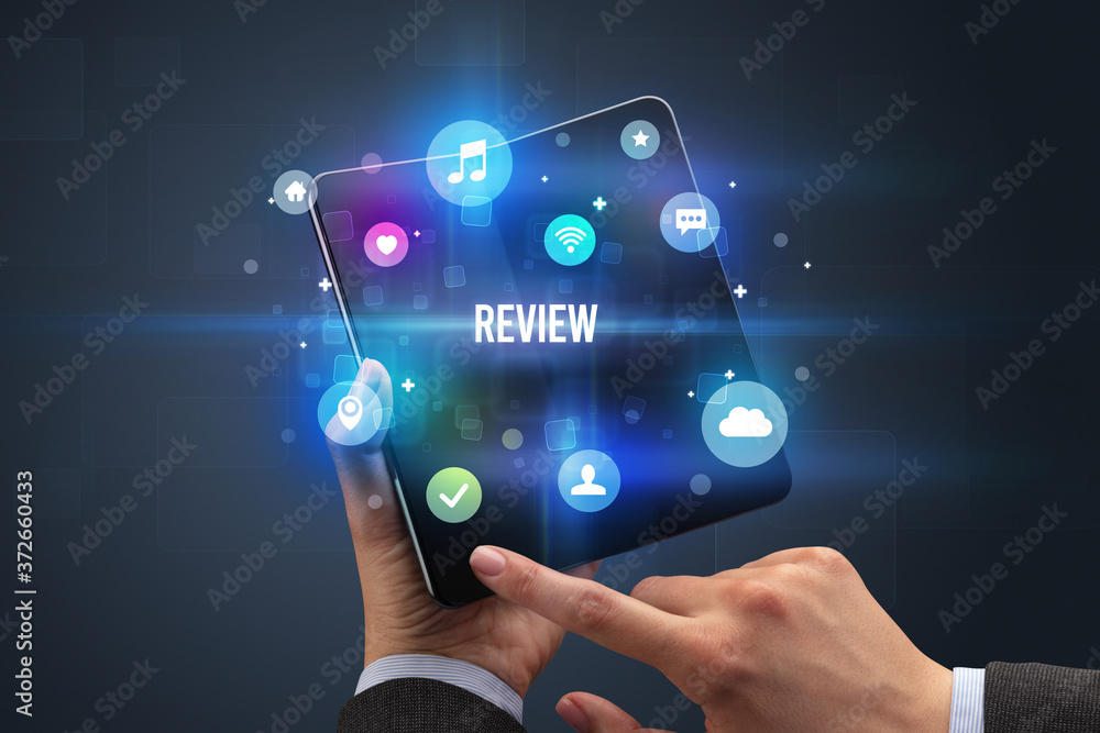 Businessman holding a foldable smartphone with REVIEW inscription, social media concept Businessman holding a foldable smartphone with REVIEW inscription, social media concept