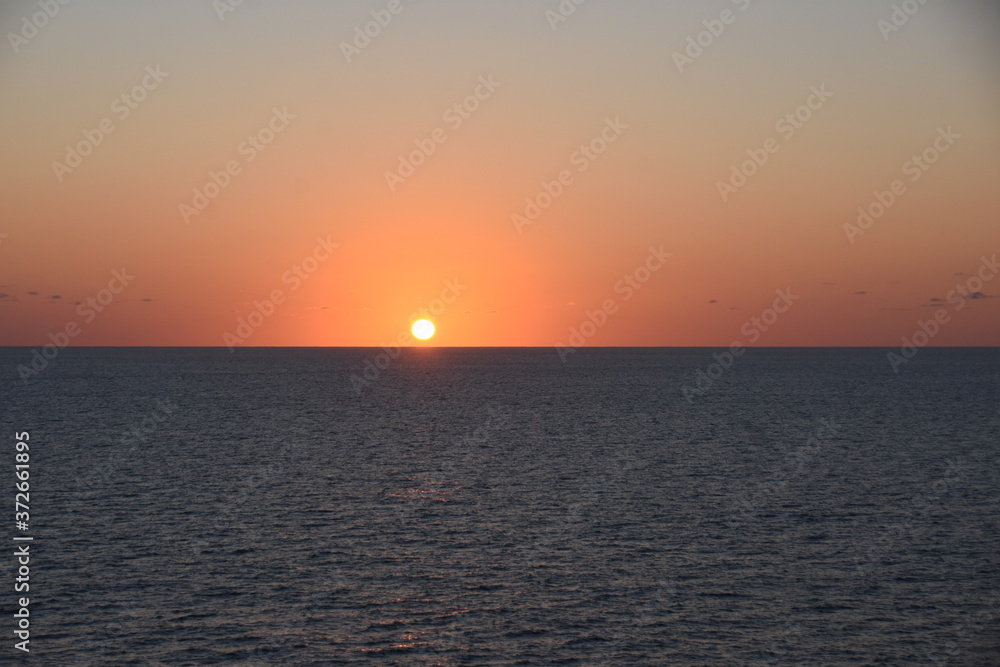 Sunset in Atlantic ocean. The sky is displayed in varies harmonic shades of red, orange and yellow during calm weather in spring time.