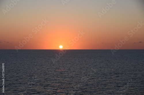 Sunset in Atlantic ocean. The sky is displayed in varies harmonic shades of red, orange and yellow during calm weather in spring time. © Lucia