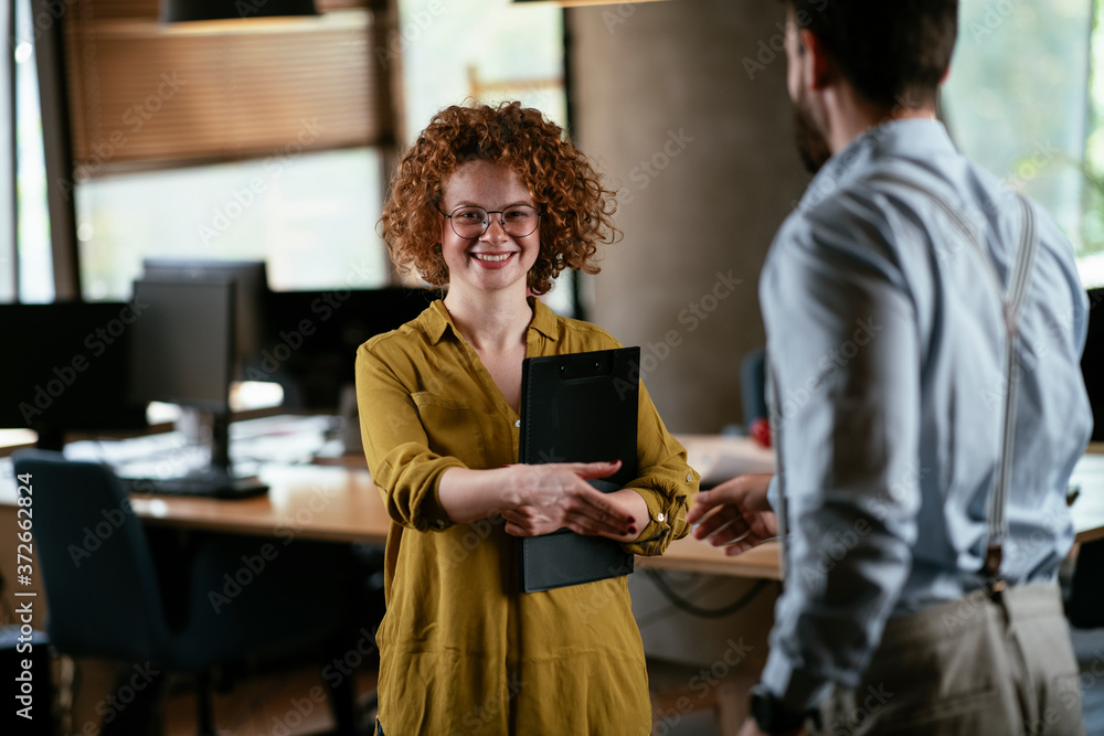 Colleagues in office. Businesswoman and businessman handshake in office Colleagues in office. Businesswoman and businessman handshake in office
