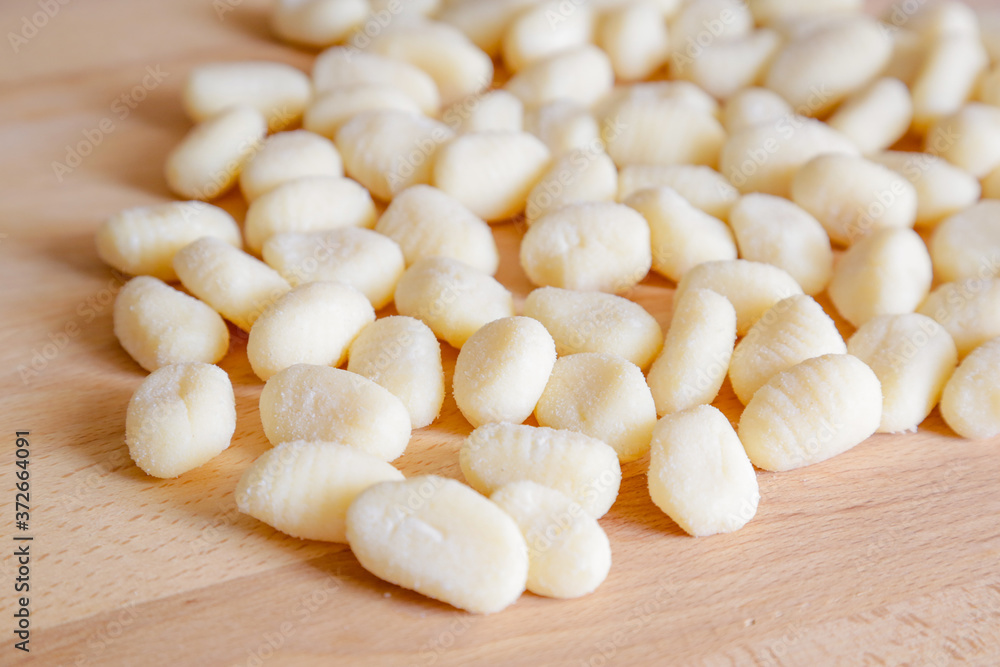 Traditional gnocchi, handmade italian pasta, with tomatoes on wooden table, natural light Traditional gnocchi, handmade italian pasta, with tomatoes on wooden table, natural light