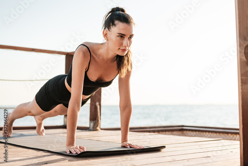 Fitness woman outdoors at the beach making plank exercise