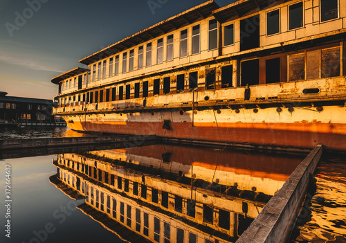 An abandoned ship is on the water. The reflection on the water. Sunset.