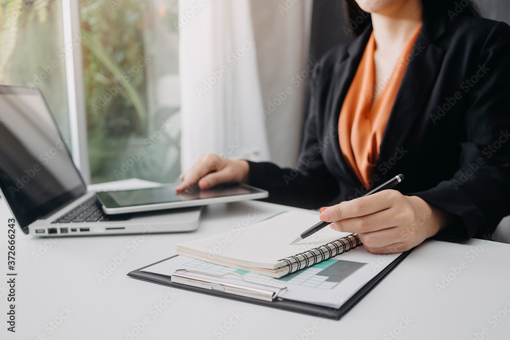 Businessman hands working with finances about cost and and laptop with tablet, smartphone at office in morning light Businessman hands working with finances about cost and and laptop with tablet, smartphone at office in morning light
