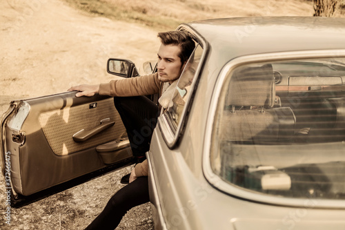 Canvastavla A handsome man driving an oldtimer car.