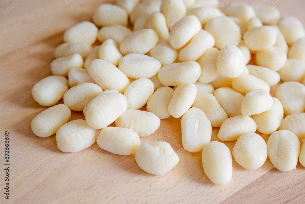 Traditional gnocchi, handmade italian pasta, with tomatoes on wooden table, natural light