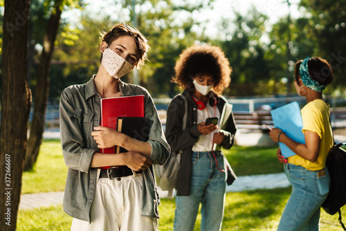 Image of multinational student girls talking and using cellphone