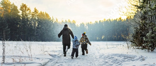 Father and two children in winter forest