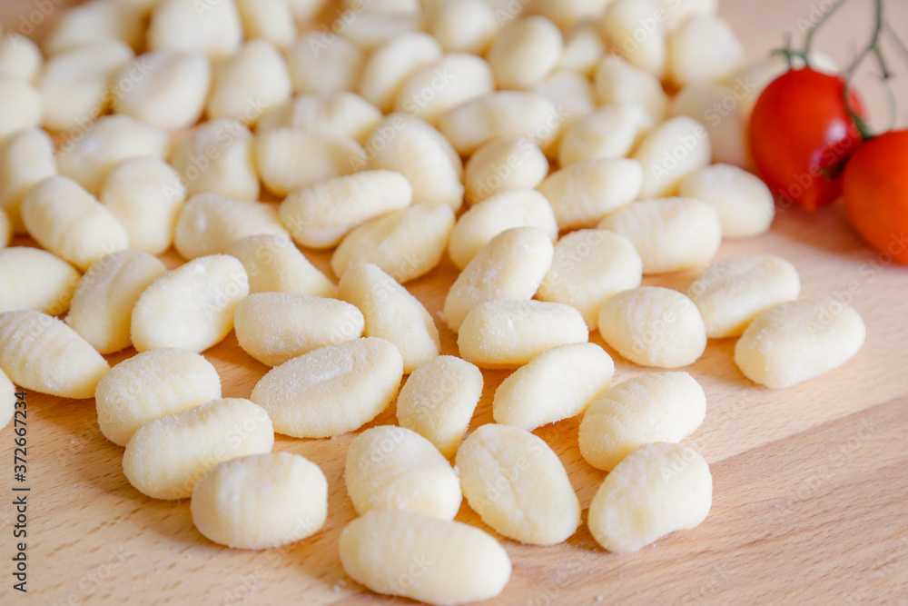 Traditional gnocchi, handmade italian pasta, with tomatoes on wooden table, natural light