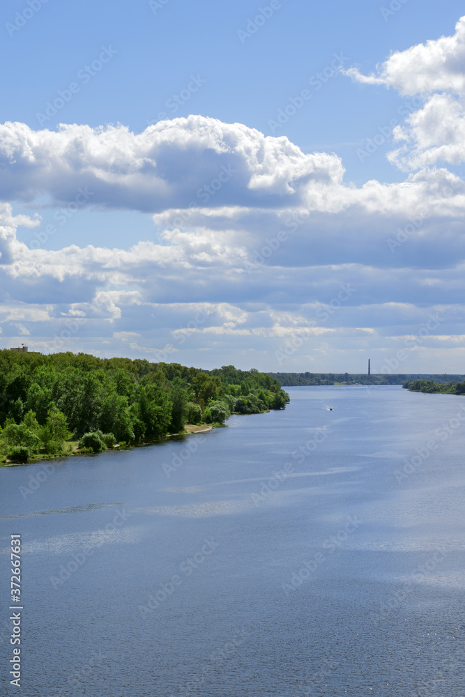 Fototapeta premium River bank covered in verdure and river bed of Volga and overcast sky on a summer day
