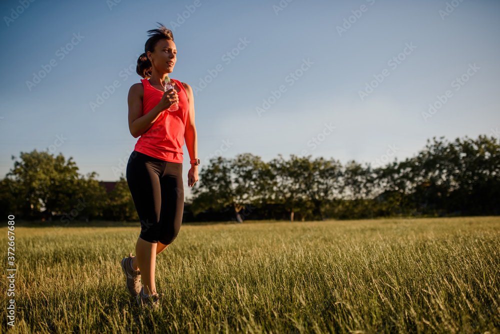 Young beautiful woman is making sport, she is running on a grass in the midst of nature on sunset. Young beautiful woman is making sport, she is running on a grass in the midst of nature on sunset.