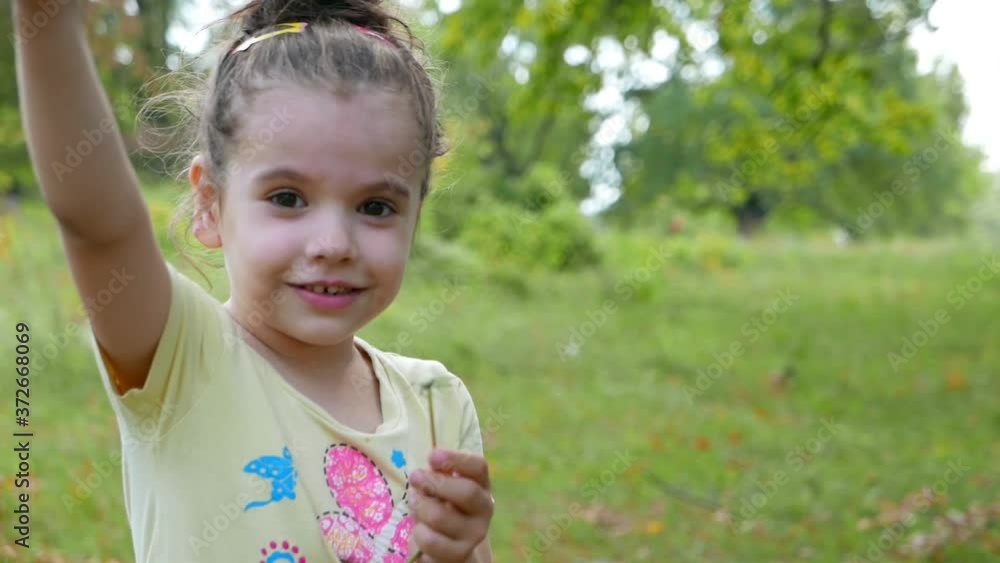 Kid girl blowing dandelion in a beautiful park outdoors Kid girl blowing dandelion in a beautiful park outdoors