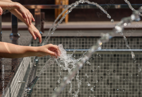 child's hands playing with the water from fountain