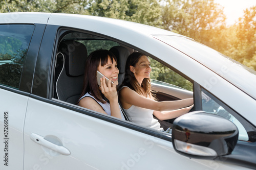 Two happy young women friends are driving a car and enjoy the company. © Med Photo Studio
