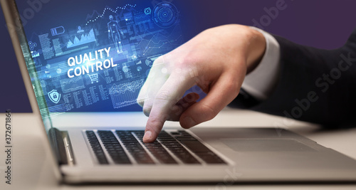 Businessman working on laptop with QUALITY CONTROL inscription, cyber technology concept