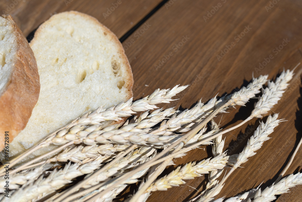White bread and wheat on rustic wood table background with copy space.