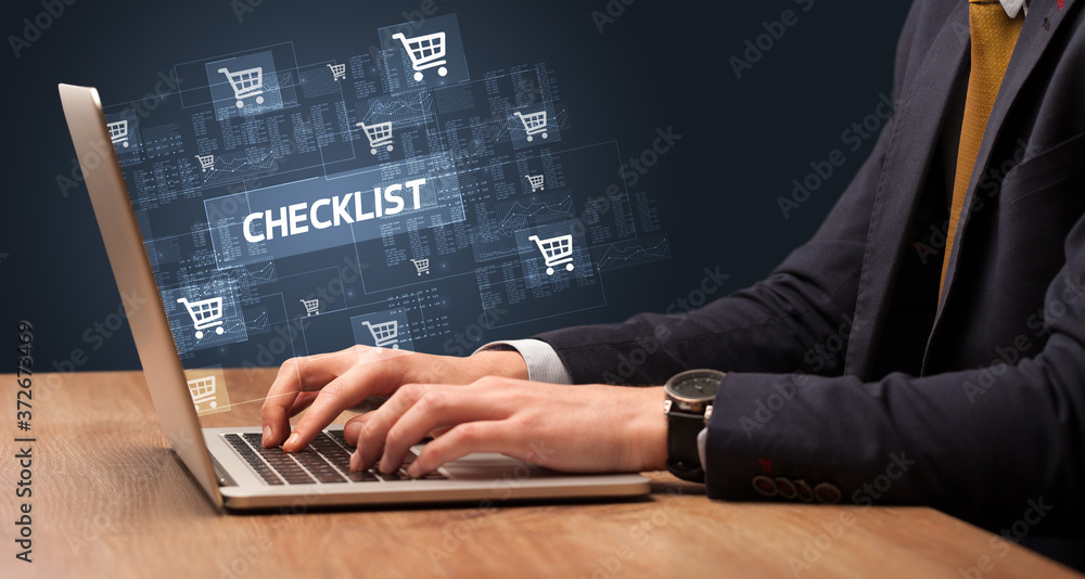 Businessman working on laptop with CHECKLIST inscription, online shopping concept Businessman working on laptop with CHECKLIST inscription, online shopping concept