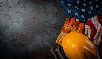 Happy Labor day concept. American flag with different construction tools on dark stone background, with copy space for text.