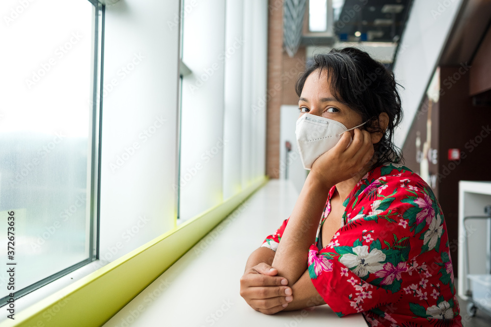upset spanish young woman at airport wearing surgical face mask,traveling during the covid-19 pandemic. Corona virus has caused a crisis in the travel and aviation industry