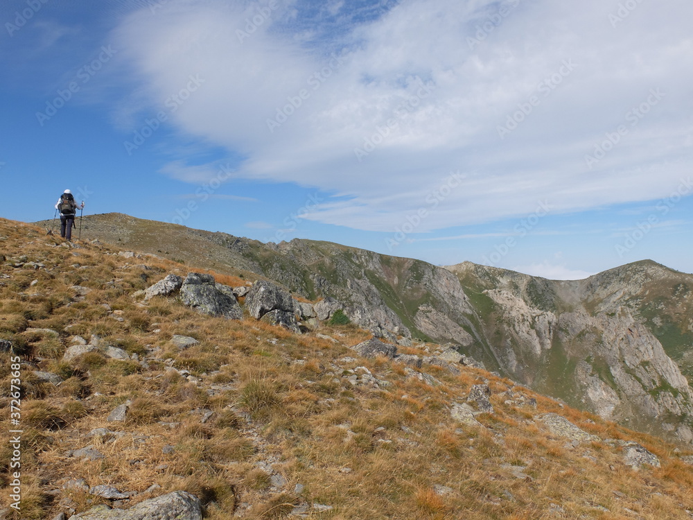 Jeune femme qui randonne en montagne hors sentier vers le massif du Madres dans les Pyrénées orientales en Occitanie