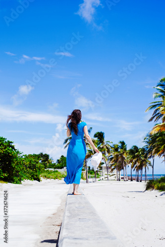 Rear view of happy woman with hat walking on the island