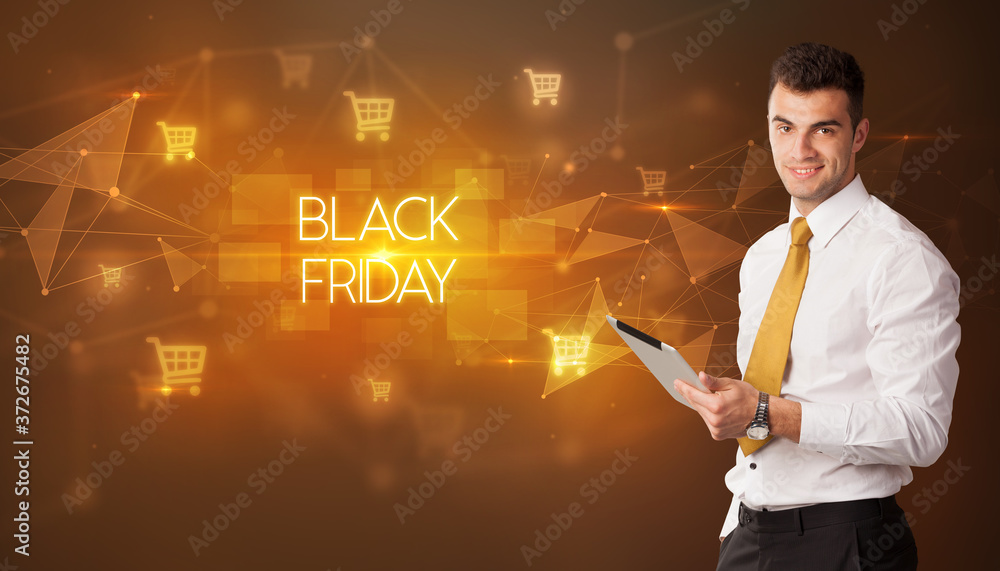 Businessman with shopping cart icons and BLACK FRIDAY inscription, online shopping concept Businessman with shopping cart icons and BLACK FRIDAY inscription, online shopping concept