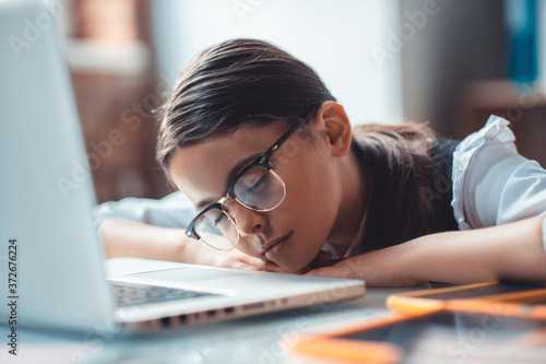 Surprised brunette girl in eyeglasses napping at the laptop