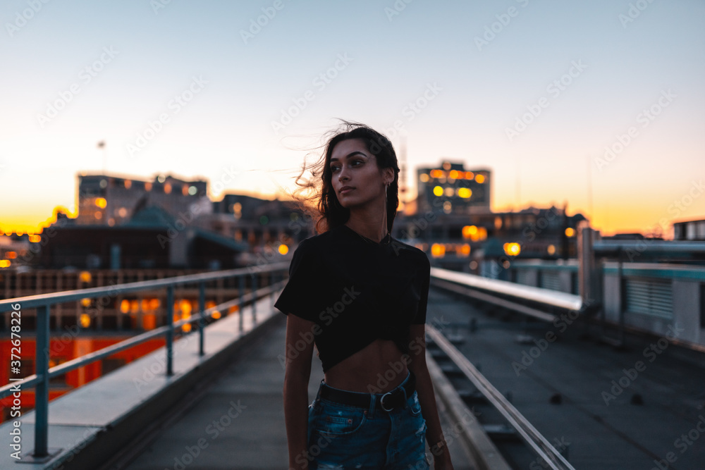Young women in black crop top shirt and shorts posing on rooftop