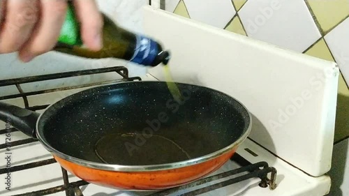 Olive oil is poured into a frying pan heated