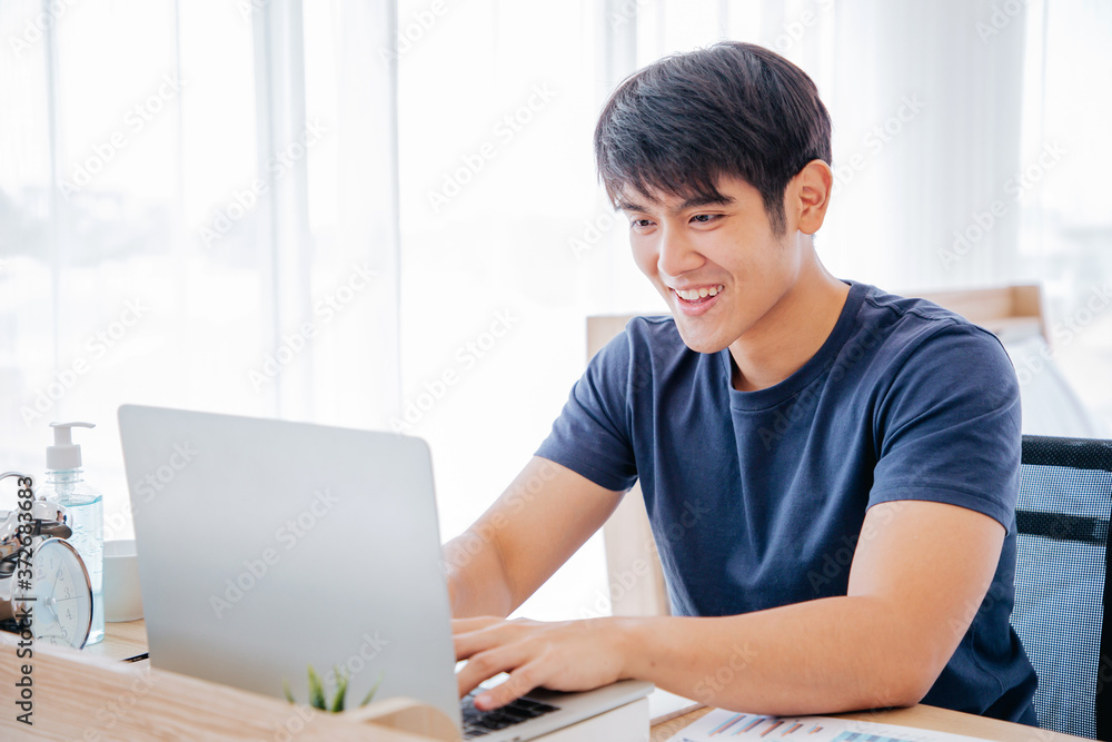 Happy Asian man using Laptop computer and checking good News, Trading, Watching Movie in the Bedroom. COPY SPACE. WORK FROM HOME Concept. Happy Asian man using Laptop computer and checking good News, Trading, Watching Movie in the Bedroom. COPY SPACE. WORK FROM HOME Concept.