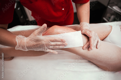 Depilation of female legs using waxing and tape. Depilation with wax in a beauty salon.