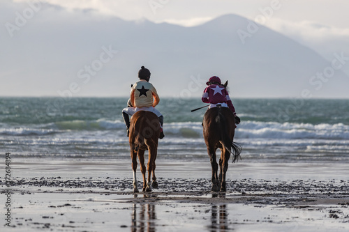 Two race horses and jockeys looking out at the ocean on the west coast of Ireland