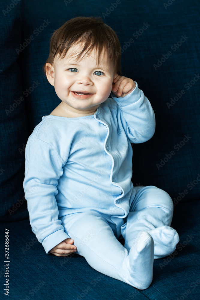 A cute little boy is playing on blue sofa. The concept of childhood, children's themes. A cute little boy is playing on blue sofa. The concept of childhood, children's themes.