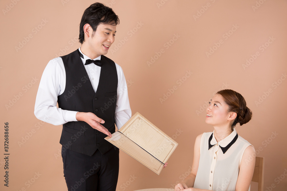 メニューの説明をするウェイターと女性客