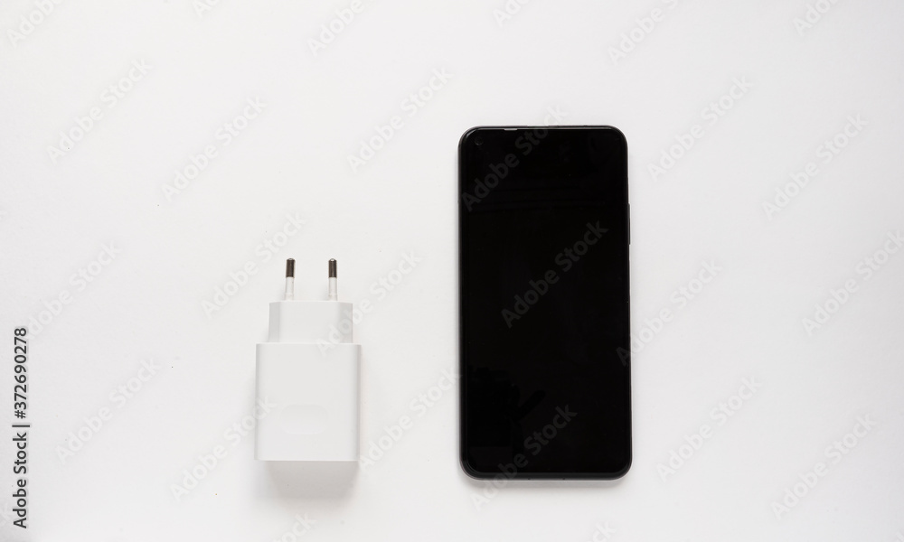 An adapter for a USB to 3.5mm type c headphone cable on a smartphone. Close up white cable and 3.5mm audio cable on blue background An adapter for a USB to 3.5mm type c headphone cable on a smartphone. Close up white cable and 3.5mm audio cable on blue background