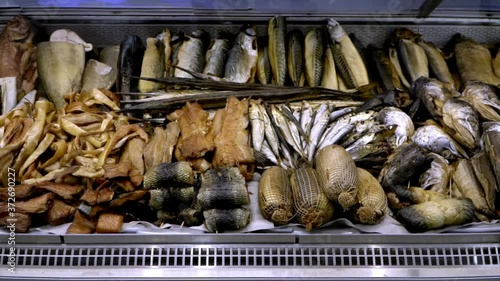 Close-up view of salted, dried, smoked fish and various seafood for sale in a supermarket showcase, slow motion
