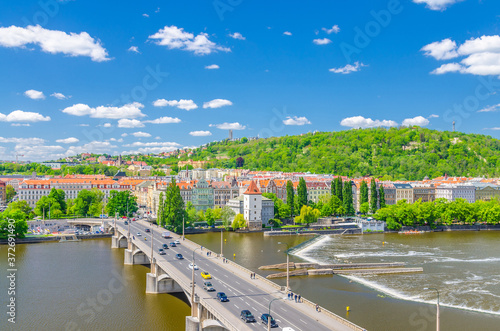 Aerial panoramic view of Prague city, historical center with Smichov district, Jiraskuv bridge, green hills, buildings along Vltava river, blue sky white clouds background, Bohemia, Czech Republic photo