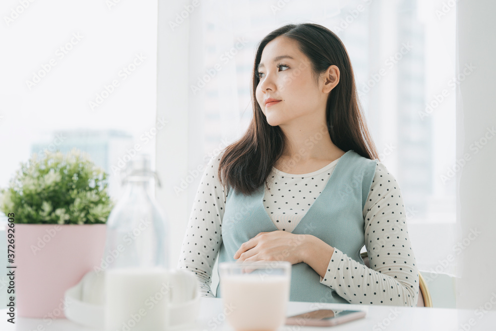 Young beautiful pregnant asian woman holding belly at home. Young beautiful pregnant asian woman holding belly at home.