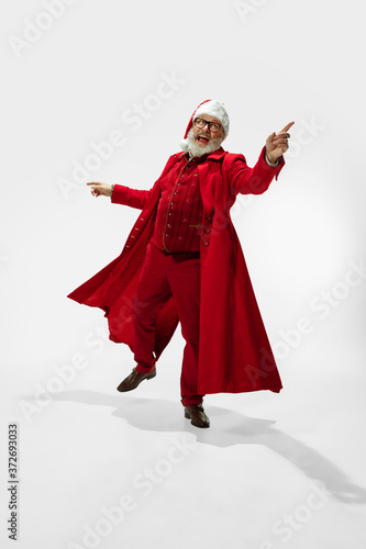 Greeting man. Modern stylish Santa Claus in red fashionable suit isolated on white background. Looks like a rockstar. New Year and Christmas eve, celebration, holidays, winter's mood, fashion.